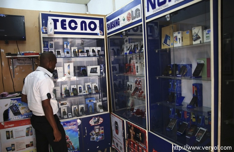 A man looks at smartphones on display at a shop at Wuse II business district in Abuja December 9, 2014. Nigeria is suffering from a plummeting currency, steep budget cuts, corruption scandals and diving oil prices; yet all this is unlikely to decide a tight race for the presidency. When the central bank devalued the naira last month to save foreign reserves, the impact was felt instantly on the streets. Nigeria imports 80 percent of what it consumes. Picture taken December 9, 2014.    REUTERS/Afolabi Sotunde  (NIGERIA - Tags: BUSINESS POLITICS) - RTR4I0KF